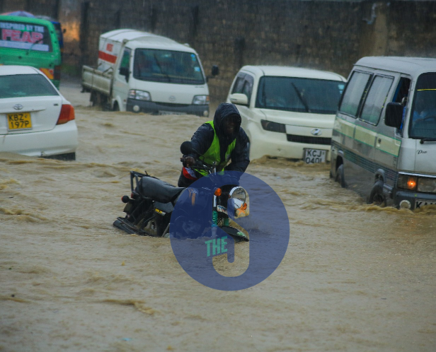 A boda boda operator pushes his bike on a flooding road after it developed a mechanical problem at kwa sonko area in Kisauni, Mombasa, on April 22, 2023