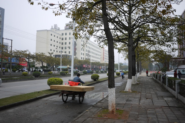 man in Zhuhai, China pushing a tricycle cart with a mattress on top