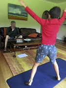 A  Pridwin Preparatory pupil  follows an online PE workout as his dad supervises. 