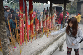 young woman placing incense sticks at Guangzhou's Renwei Taoist Temple