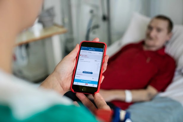 A medical professional using the Streams app by a patient's bedside.