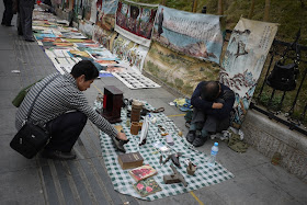 a man sleeping next to his items for sale outside Tianxinge Antique City in Changsha, China