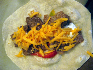 Beef fajitas on a tortilla topped with shredded cheese. 