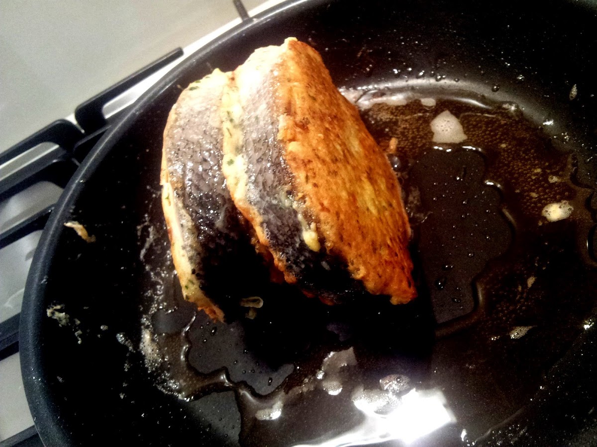 Parmesan crusted salmon frying in the pan on the skin