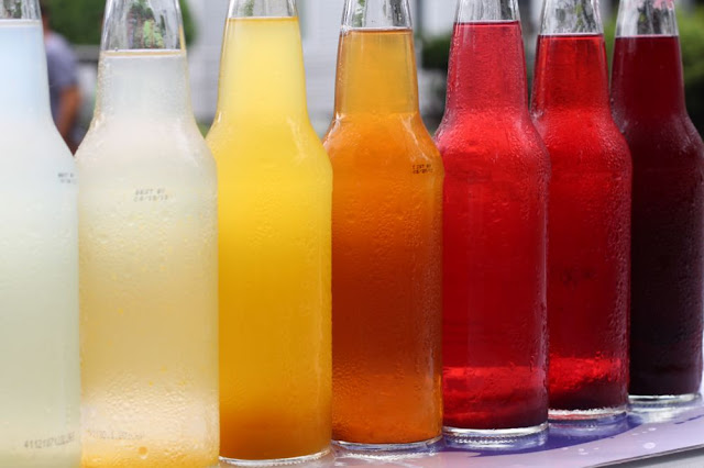 a row of bottles of locally-made soda, arranged from lightest to darkest