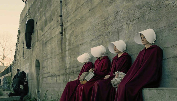 Handmaids take a breather at a gallows for dissidents during a shopping trip in 'The Handmaid's Tale' Season 1.