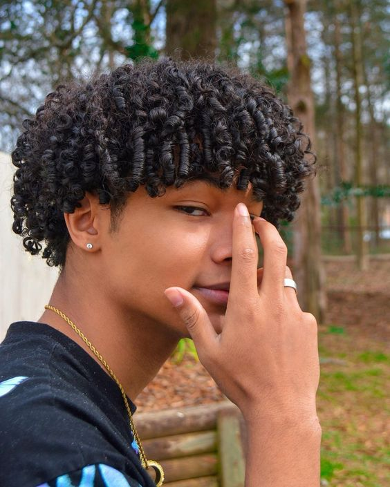 a young man wearing short curly hairstyles for men