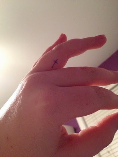 small cross tattoo on his finger