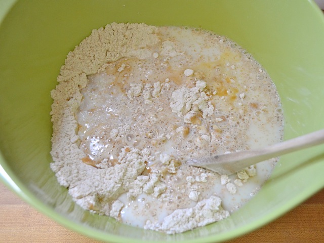 wet ingredients added to dry ingredients in mixing bowl with wooden spoon to mix 