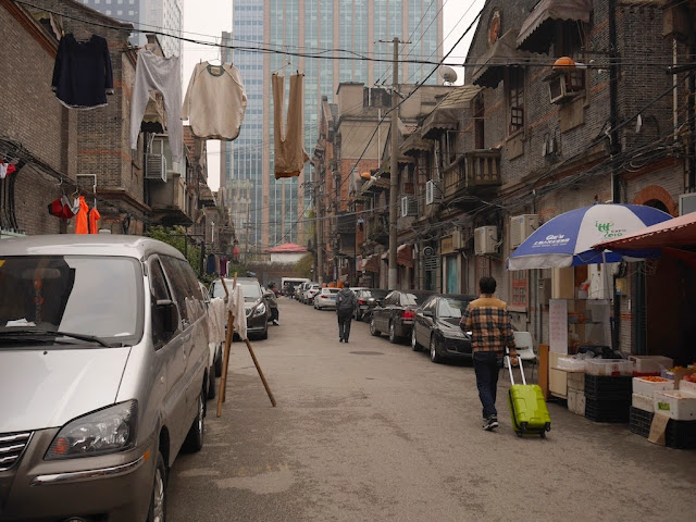 person pulling wheeled luggage at a lane south of Nanjing West Road