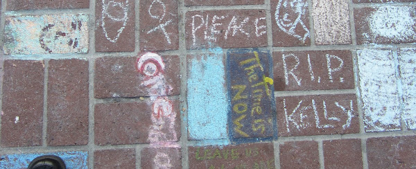 Chalk drawings on the brick pavement near the site where Kelly Thomas was beaten to death, and where his memorial now sits.