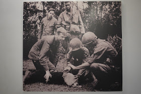 man with a cloth covered face being held down by U.S. military members