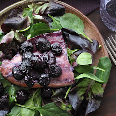 spinach salad on a plate with salmon and roasted purple grapes