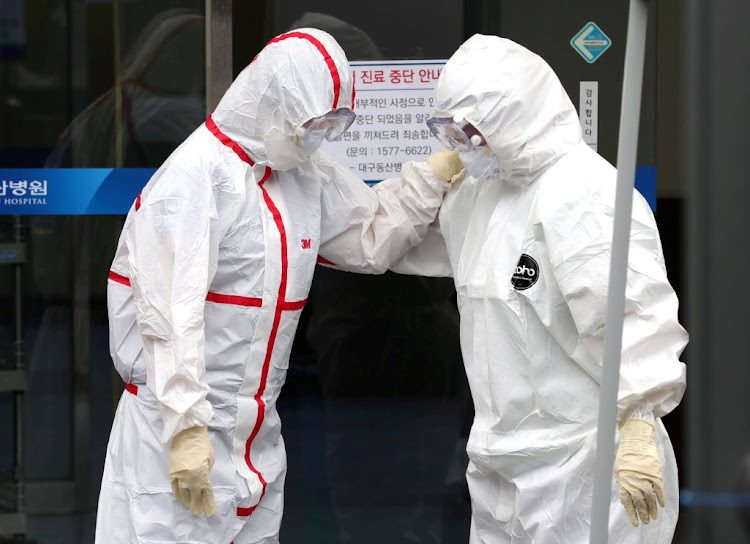 Medical workers wearing protective gears comfort each other outside a hospital in Daegu, South Korea, on February 28 2020, following the outbreak of the coronavirus.