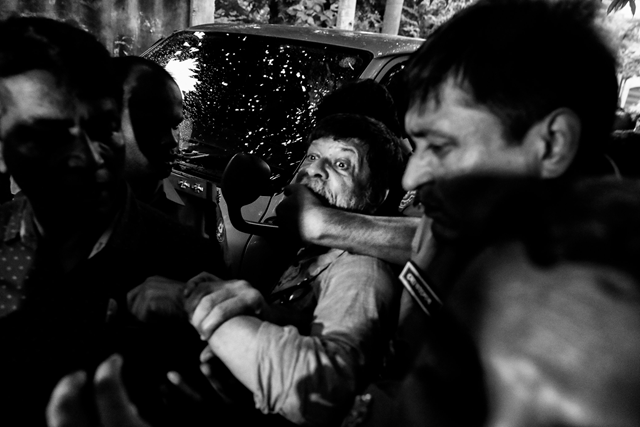 A Bangladeshi police officer grabs the mouth of photographer Shahidul Alam, preventing him from speaking to the press during a court appearance in Dhaka, Bangladesh, on 6 August 2018. Alam was arrested after criticizing the government in an interview. Photo: Suvra Kanti Das / TIME