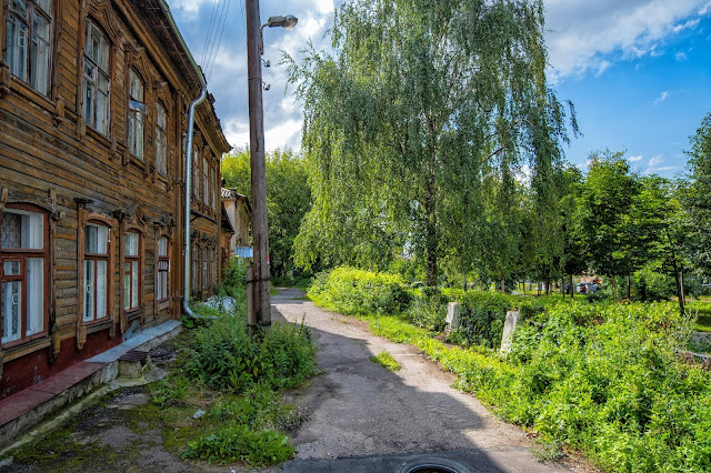 Слева старые деревянные дома, справа сквер