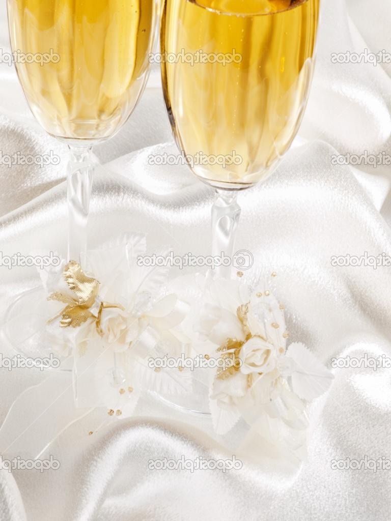 Two glasses with champagne and wedding decoration on white silk