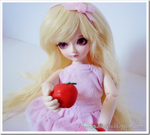 A ball jointed doll trying to choose between a healthy apple and cake.