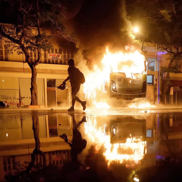 A man walks past a burning bus after demonstrators from the group Black Bloc set fire to it during a protest in Rio de Janeiro.