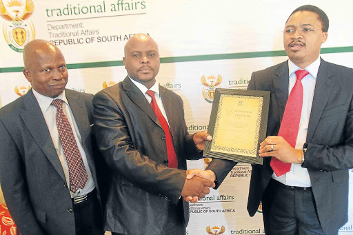 CONFIRMATION: Former traditional affairs MEC Mlibo Qoboshiyane, right, is seen in this 2012 file picture handing over a certificate of kingship recognition to AmaMpondo King Zanozuko Tyelovuyo Sigcau, centre, while national Traditional Affairs director-general Professor Charles Nwaila looks on at an event in Port Edward Picture: LULAMILE FENI