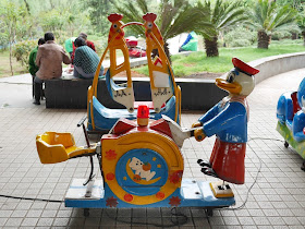 kiddie ride resembling half a seesaw with a duck character holding one end end to push it up and down