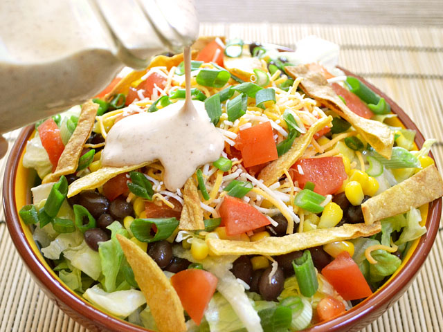 bowl of southwest taco salad with ranch being poured on top 