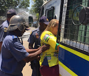 Arrested ANC member escorted into a police vehicle following protests outside Hoerskool Overvaal, Vereeniging.