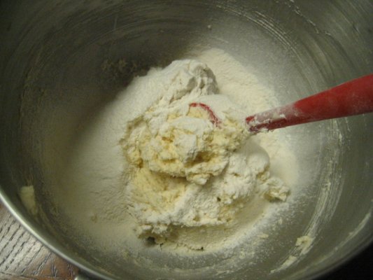 Dump all the flour in at once, and use spatula and mix by hand.  Trust me, a lot less mess doing this way.