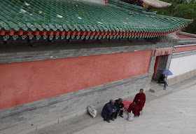 Tibetan monk and two other men sitting at Kumbum Monastery (Taer Si) in Qinghai, China