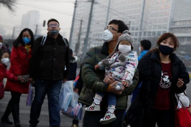 People wear face masks as they cross a street on a polluted day in Beijing, China, on 4 January 2017. Photo: Thomas Peter / REUTERS