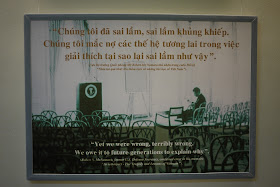 poster reading "'Yet we were wrong, terribly wrong. We owe it to future generations to explain why.' Rober S. McNamara, former U.S. Defense Secretary, confessed error in his memoirs 'In retrospect - The Tragedy and Lessons of Vietnam'."