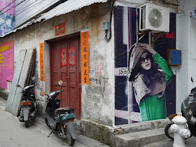 a fashionable advertisement on the wall of an older building with red doors in Yangjiang