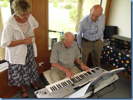 Rob Powell playing the Yamaha Tyros 4 with potential new member, Elizabeth and David Collett watching-on with keen interest.