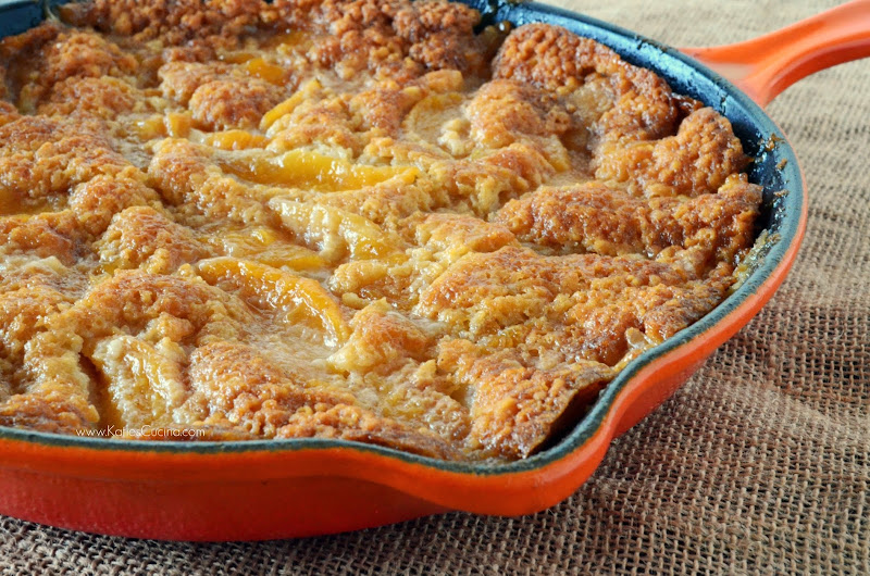 Orange skillet filled with peach cobbler on a burlap cloth.