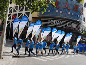 group of people marching down the street wear Vivo shirts and hold Vivo promotional signs