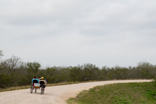 People ride a bike along the levee near the National Butterfly Center in Mission, Texas on Wednesday 6 February 2019. The center will have about 70 percent of its property cut off by the proposed Trump border wall along the levee in the area. Photo: Courtney Sacco / Caller-Times