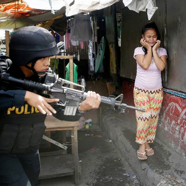 A resident cries as a SWAT member of the Philippine National Police searches for residents who allegedly threw rocks at them as they enforce the demolition of their shanties at the sprawling community of informal settlers Monday, Jan. 27, 2014 at suburban Quezon city, northeast of Manila, Philippines.