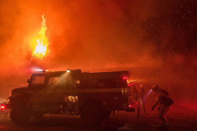 Firefighters work to save structures from a wildfire on Soda Canyon Road in Napa, California, on Monday, 9 October 2017. Photo: Noah Berger / The San Francisco Chronicle