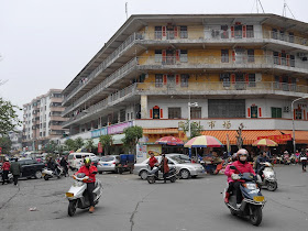 motorbikes at an intersection with a large yellow building in Yangjiang, China