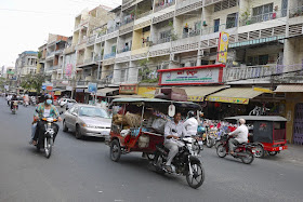 man driving tuk-tuk filled with goods