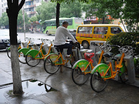 man using a propped-up docked city bicycle as a stationary exercise bicycle