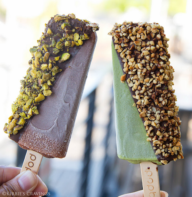 photo of a chocolate hazelnut, half dipped in milk chocolate and covered in chopped pistachios.