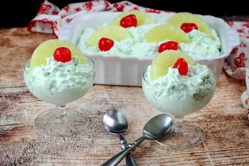 Small bowls of Cottage Cheese Jell-O Salad with pineapple and a cherry on top.