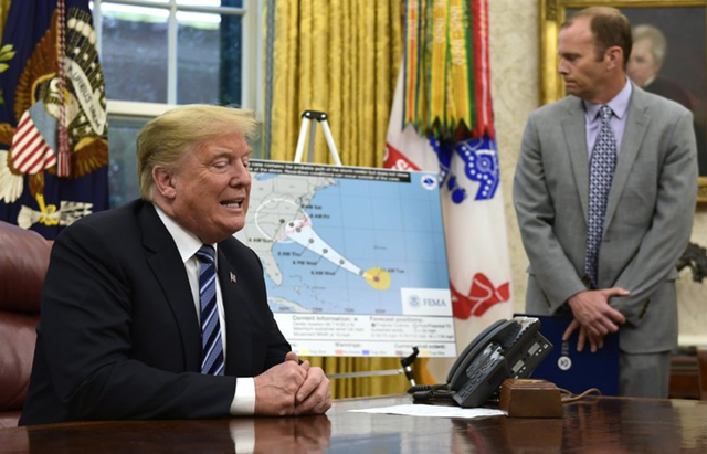 Donald Trump, left, talks about Hurricane Florence during a briefing in the Oval Office of the White House in Washington, Tuesday, 11 September 2018, as FEMA Administrator Brock Long listens at right. Photo: Susan Walsh / AP Photo