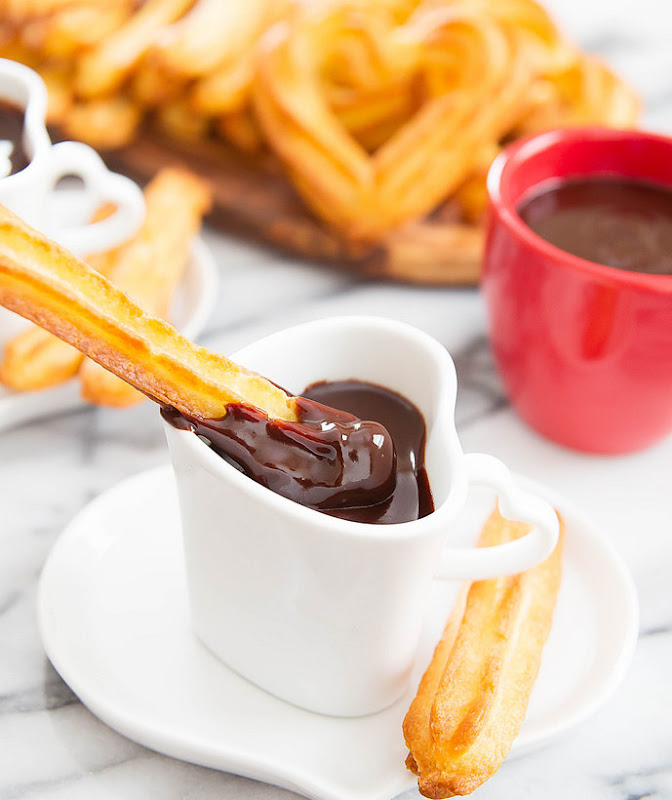 photo of a churro stick being dipped in chocolate