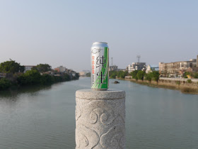 Tall can of Tsingtao Draft beer with the Moyang River in the background