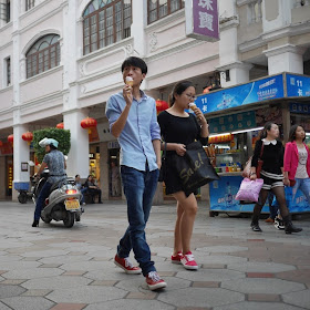 young man and young woman walking on a Sunwen West Road Pedestrian Street while eating ice cream