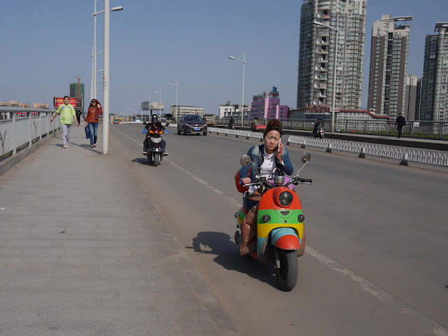 woman using a mobile phone while driving a multi-colored motorbike