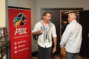 Cape Umoya United official Roger de Sa (L) crosses paths with Cape Town City owner John Comitis (R) after a meeting of the 32 clubs in the Premier Soccer League on March 18 2020 at OR Tambo International Airport in Johannesburg.