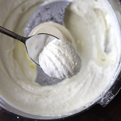 whipped feta in food processor with a spoonful being lifted out of the work bowl